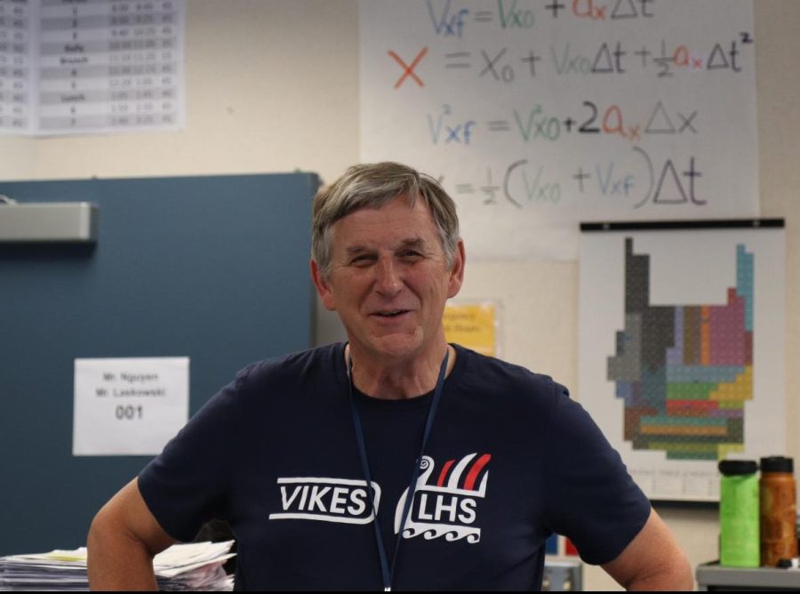 Larry Laskowski shares room 001 with fellow physics teacher Thanh Nguyen. Laskowski poses in front of a poster with the equations of motion often used in Physics class.