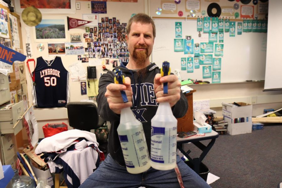 Social studies teacher Jeffrey Bale poses with bottles of disinfectant.