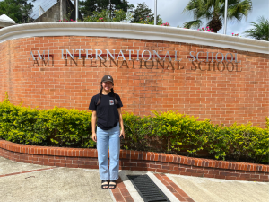 Alumna Bethany Chan stands in front of school gates, excited for her teaching-filled year ahead. 