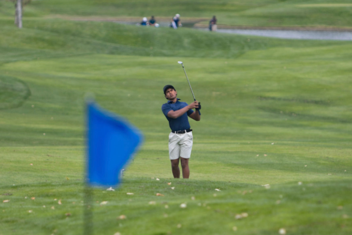 Senior Adithya Venkataraghavan swings his golf club, hitting the ball up the green hill. Photo used with permission by Adithya Venkataraghavan.