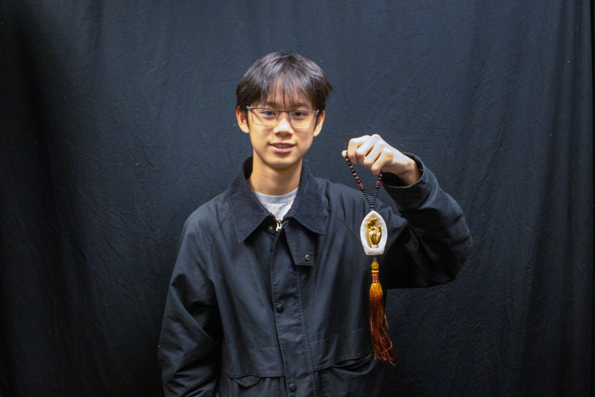 Junior Brian Lee holds up prayer beads, a symbol of his atheist identity amid his Buddhist family.